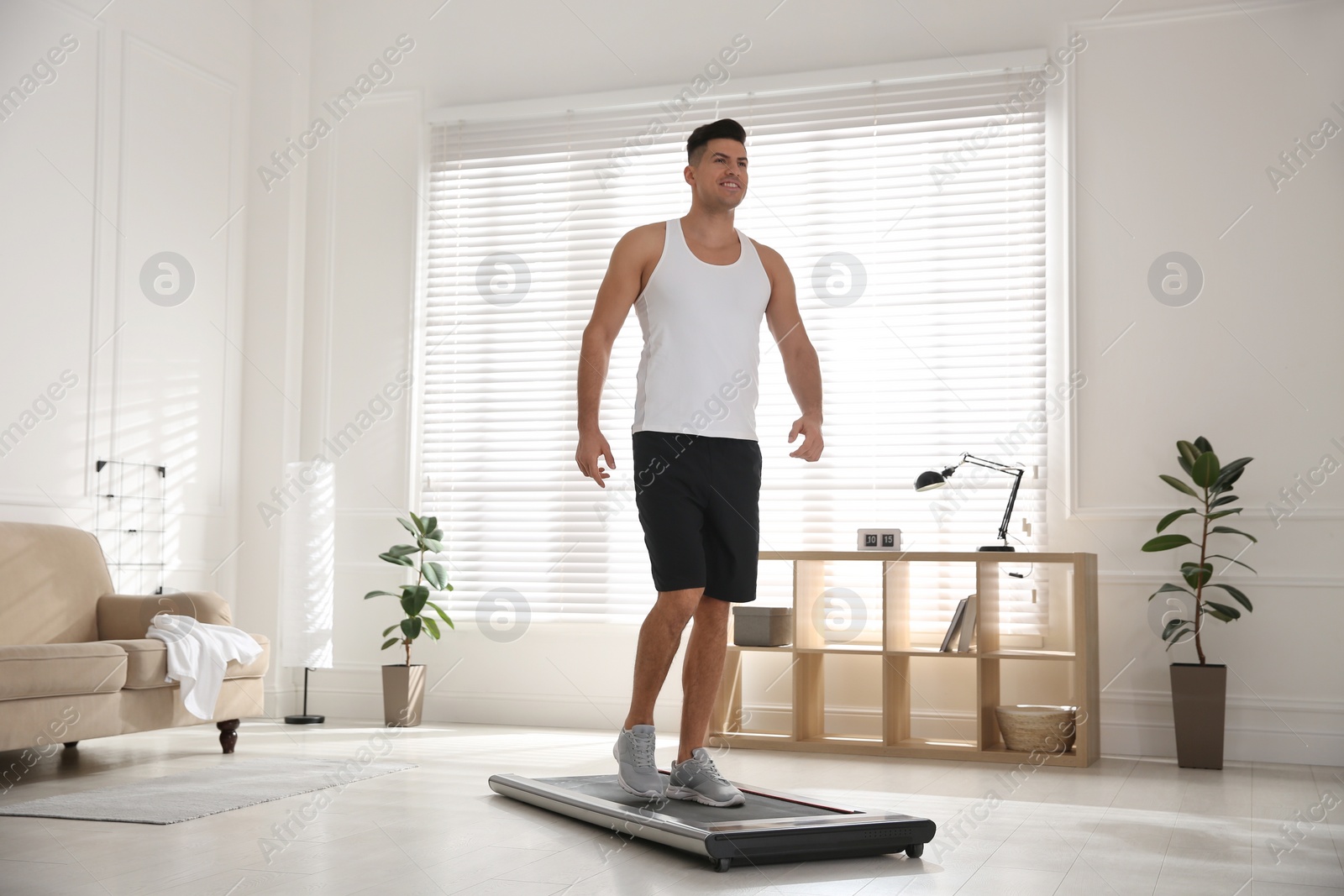 Photo of Sporty man training on walking treadmill at home