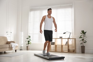 Sporty man training on walking treadmill at home