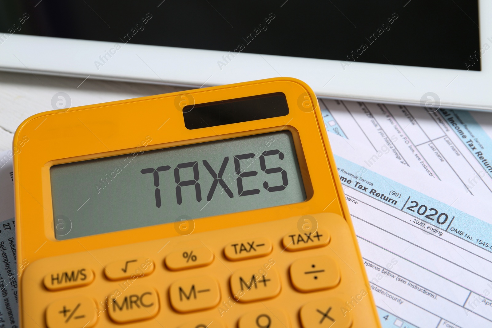 Image of Calculator with word Taxes, tablet and documents, closeup