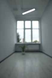 Photo of Blurred view of empty office room with windows and potted houseplants