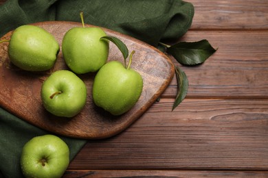 Photo of Ripe green apples with leaves and water drops on wooden table, flat lay. Space for text