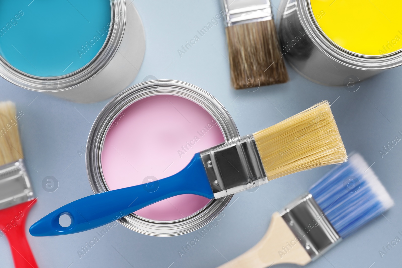 Photo of Cans with colorful paints and brushes on light background, flat lay