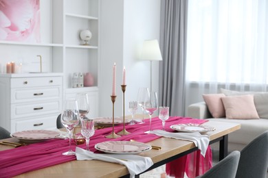 Photo of Beautiful table setting with burning candles and pink accent in dining room