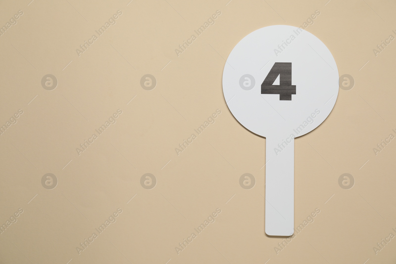 Photo of Auction paddle with number 4 on beige background, top view. Space for text