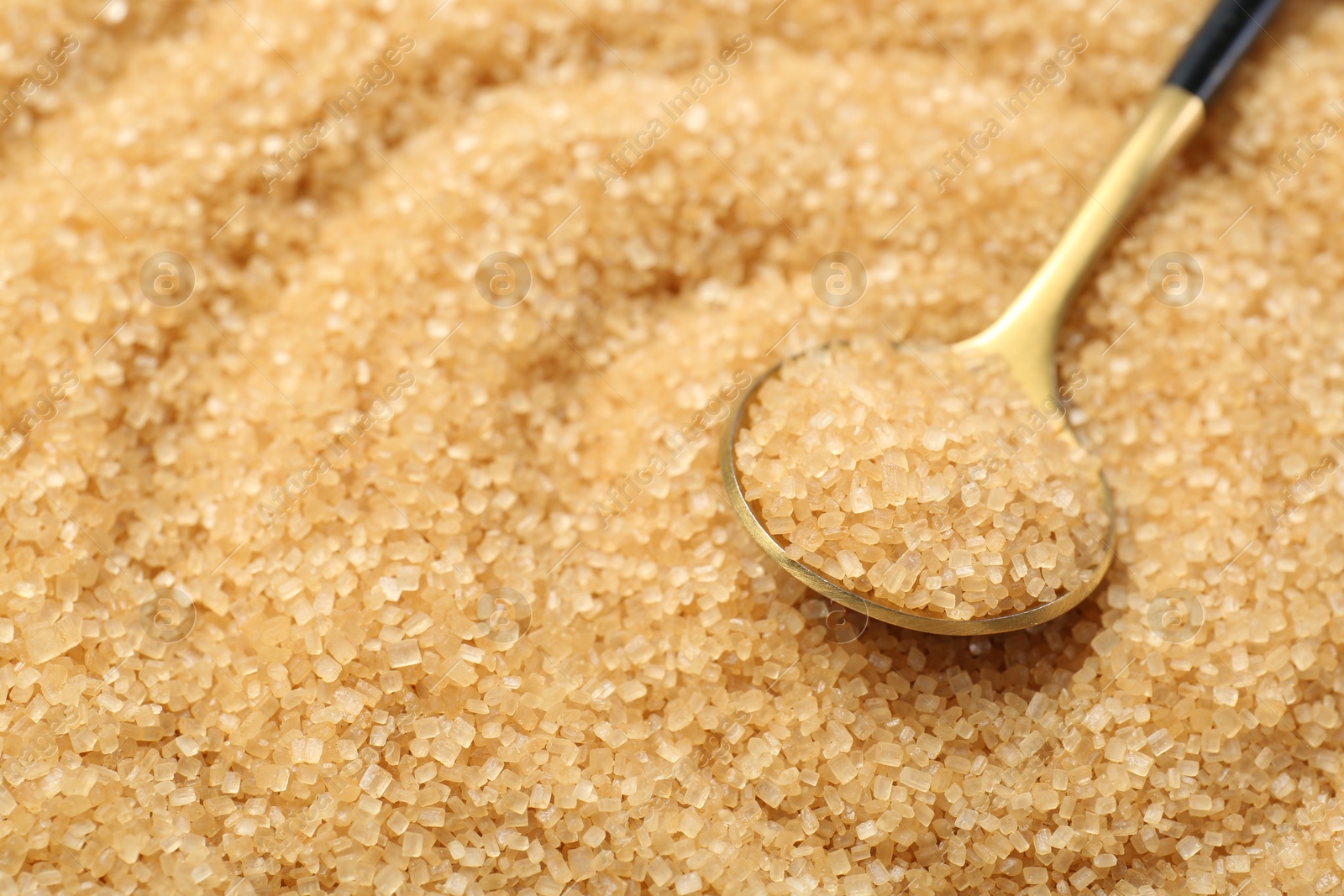 Photo of Spoon on granulated brown sugar, closeup view