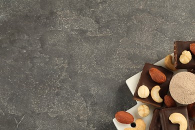 Photo of Different tasty energy bars, nuts and protein powder on grey table, top view. Space for text