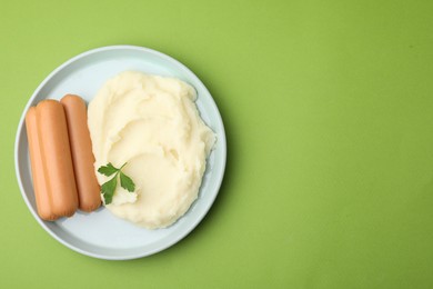 Photo of Delicious boiled sausages, mashed potato and parsley on green background, top view. Space for text