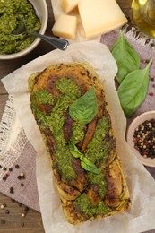 Photo of Freshly baked pesto bread with ingredients on table, flat lay