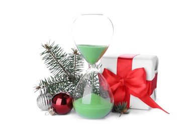 Photo of Hourglass, gift and fir tree twig with balls on white background. Christmas countdown