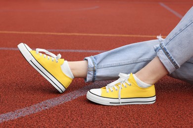 Woman wearing yellow classic old school sneakers on court outdoors, closeup