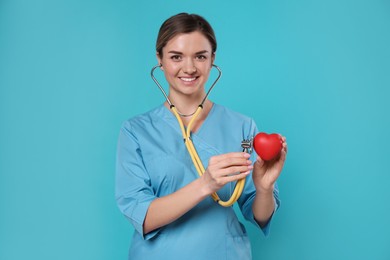 Photo of Doctor with stethoscope and red heart on light blue background. Cardiology concept