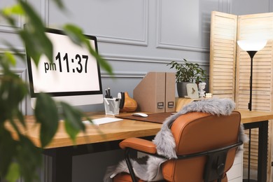 Photo of Stylish workplace with computer, houseplants and stationery on wooden desk near grey wall at home