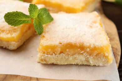 Photo of Tasty lemon bar with powdered sugar and mint on board, closeup