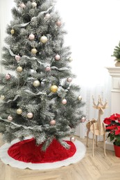 Beautifully decorated Christmas tree with skirt indoors
