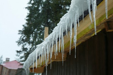 Photo of House with icicles on roof, space for text. Winter season