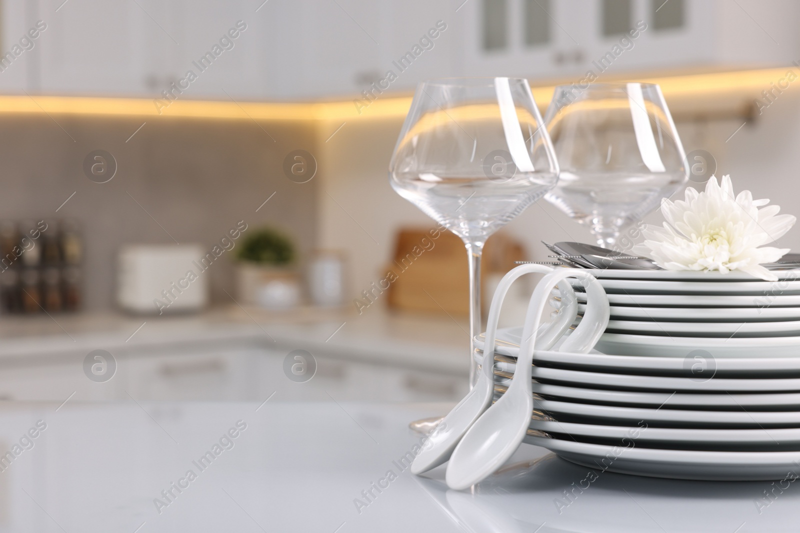 Photo of Set of clean dishware, glasses, cutlery and flower on table in kitchen, space for text