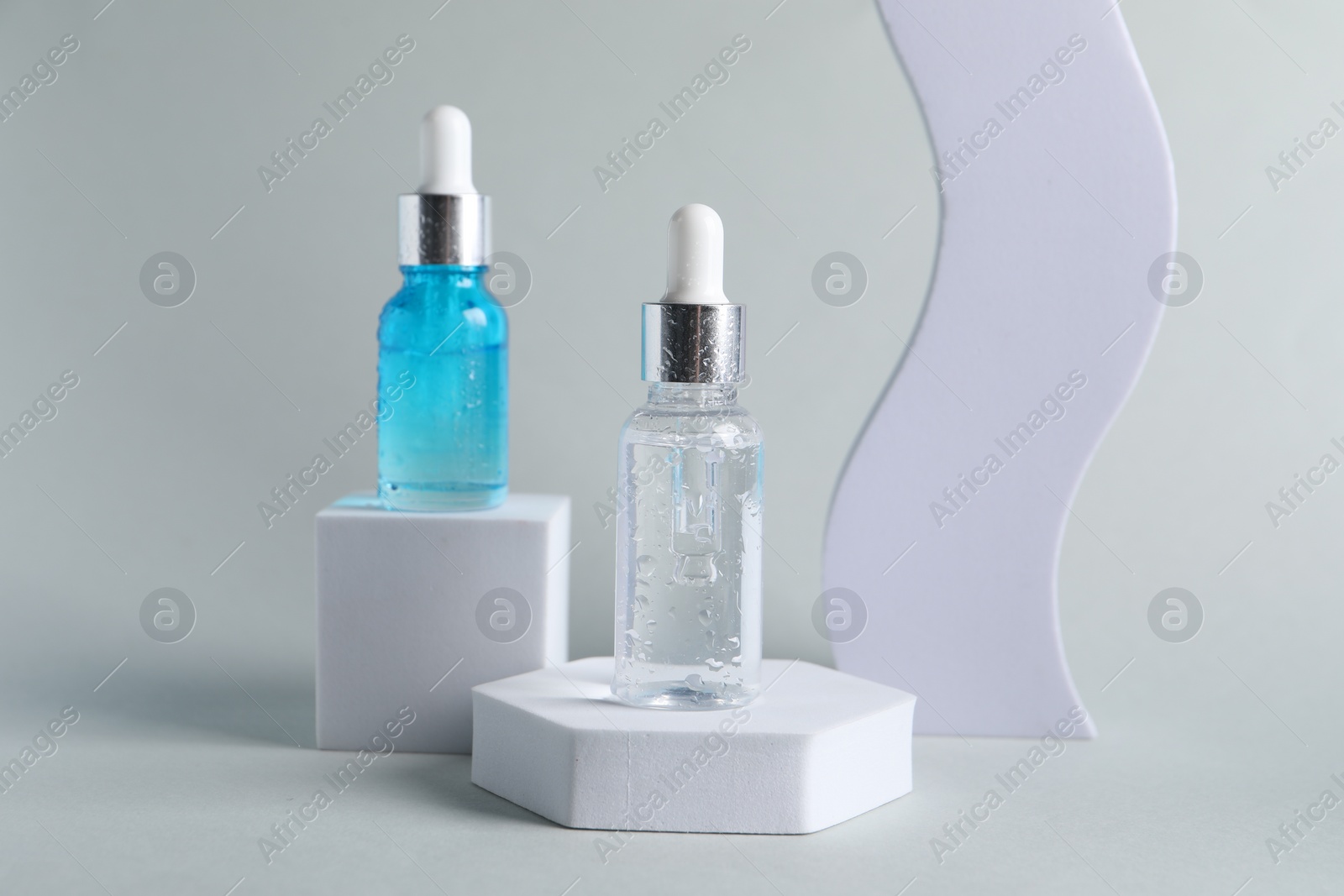 Photo of Presentation of bottles with cosmetic serums on light grey background