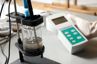 Scientist measuring acidity and pH of soil at table, closeup. Laboratory analysis