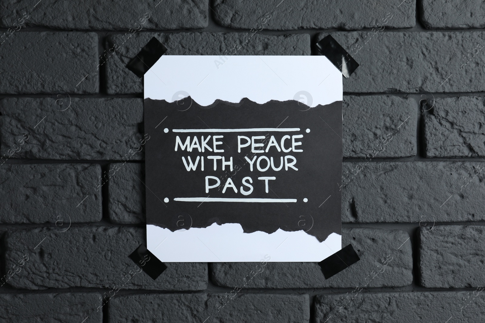 Photo of Card with life-affirming phrase Make Peace With Your Past on dark brick wall