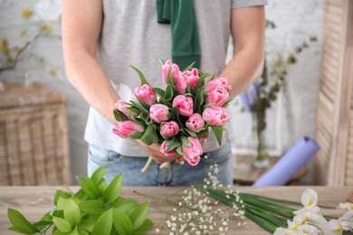 Male decorator creating beautiful bouquet at table