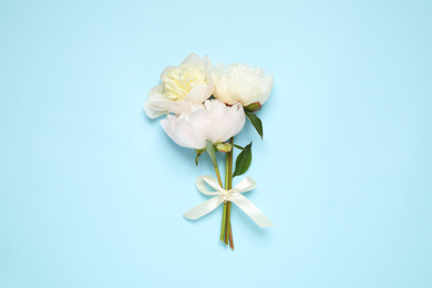 Beautiful bouquet of fresh peonies on light blue background, flat lay