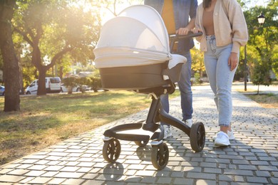 Photo of Parents walking with their baby in stroller at park on sunny day, closeup