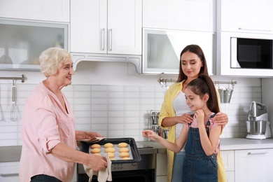 Photo of Happy grandmother helping her family to bake cookies in kitchen