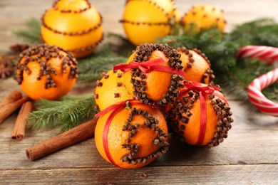 Photo of Pomander balls made of fresh tangerines with cloves  on wooden table. Christmas atmosphere