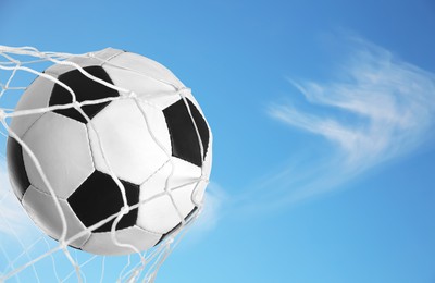 Image of Soccer ball in net against blue sky