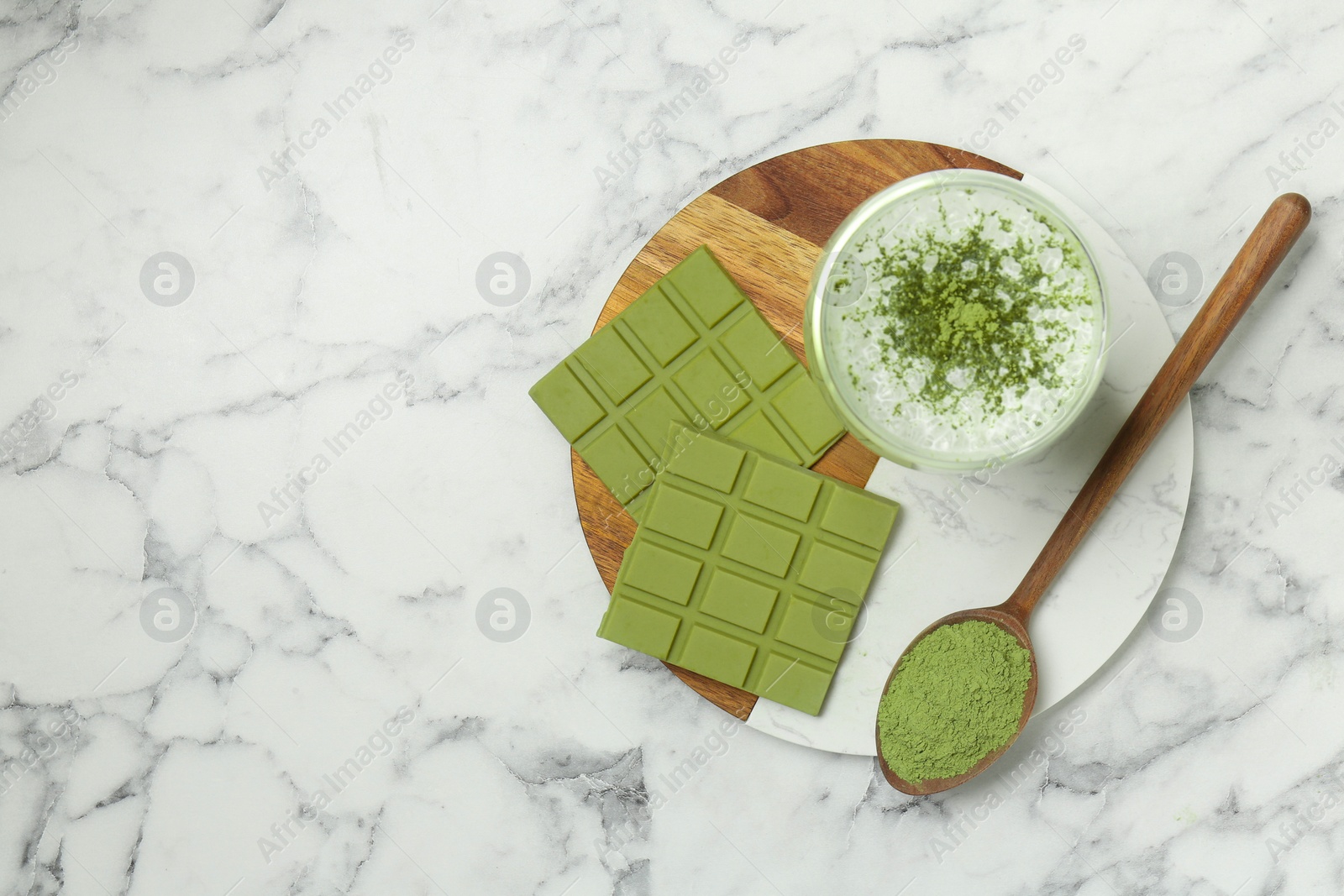 Photo of Pieces of tasty matcha chocolate bar, drink and powder on white marble table, top view. Space for text