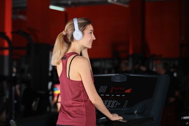 Photo of Young woman listening to music with headphones at gym