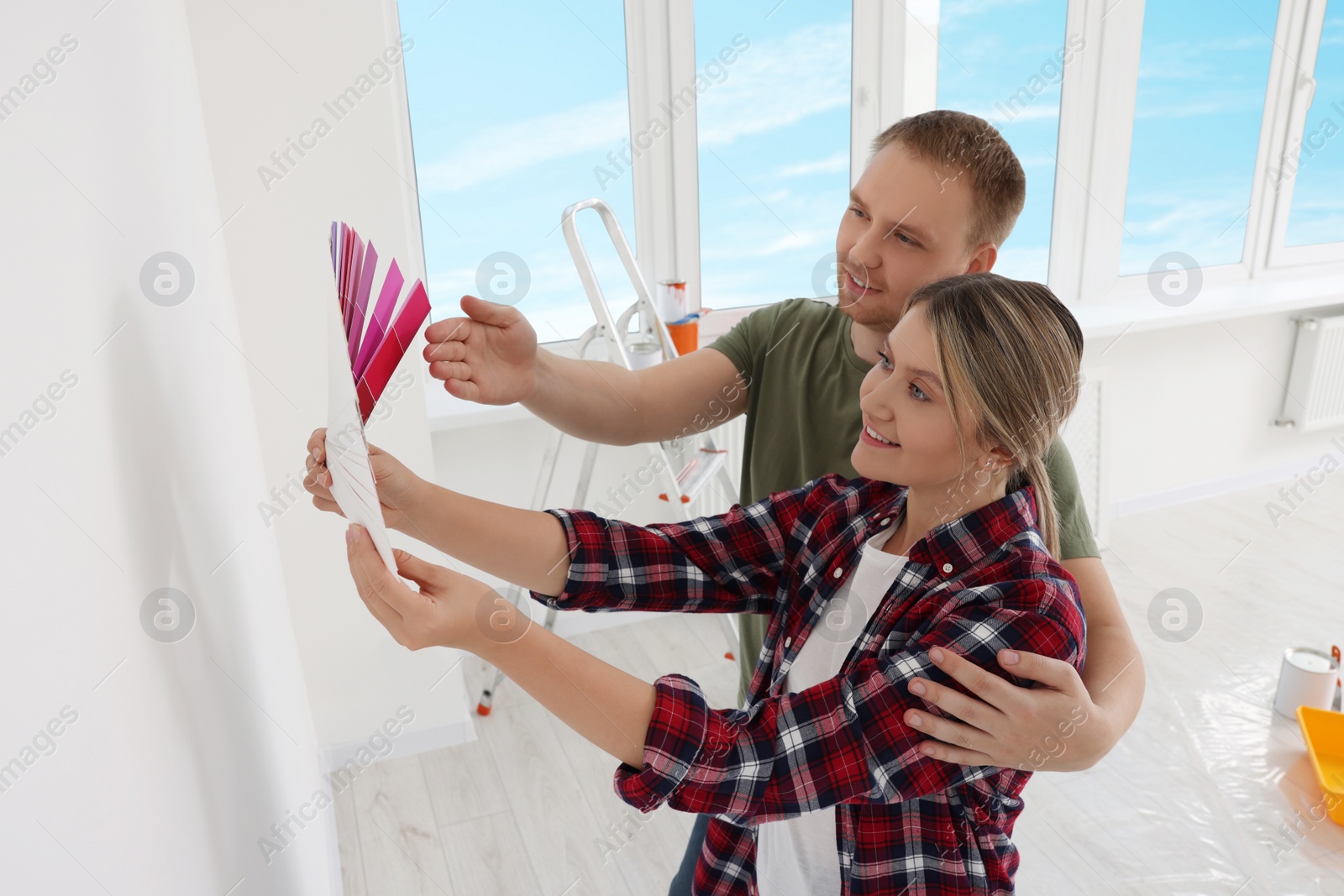 Photo of Couple with paint chips discussing new wall color in apartment during repair, above view. Space for text