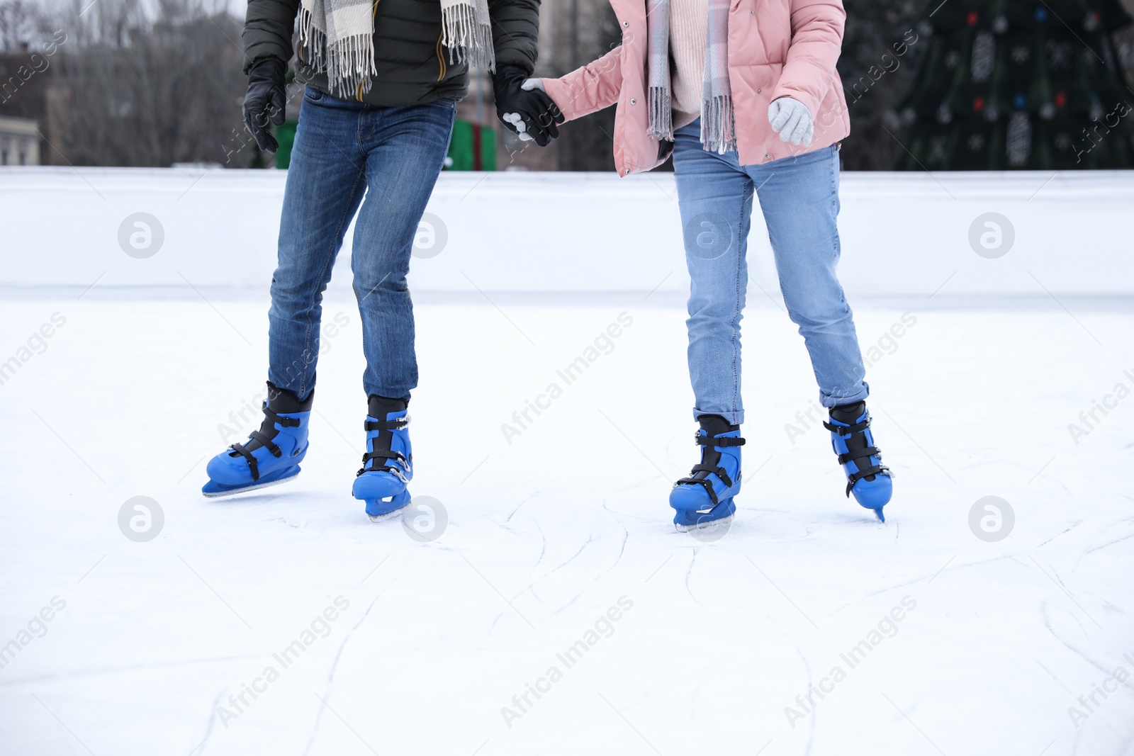 Image of Couple skating along ice rink outdoors, closeup