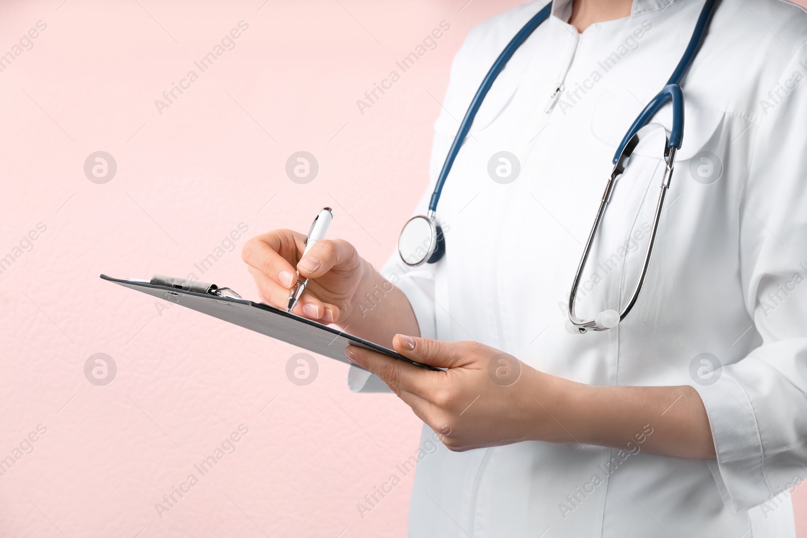 Photo of Doctor with stethoscope and clipboard on pink background, closeup. Medical service