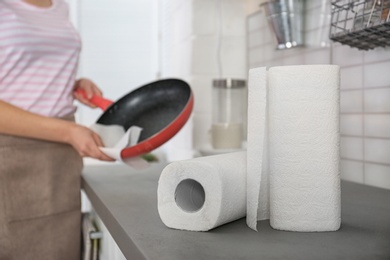 Photo of Woman wiping frying pan in kitchen, focus on paper towels