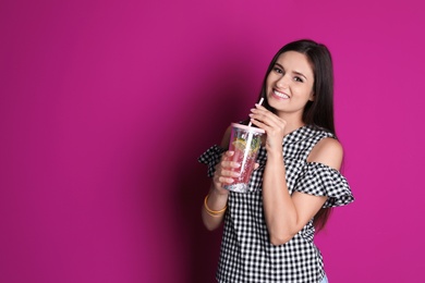 Photo of Young woman with tasty lemonade on color background. Natural detox drink