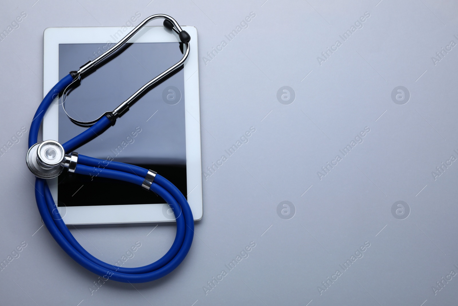 Photo of Medical stethoscope and tablet on white background, top view. Space for text