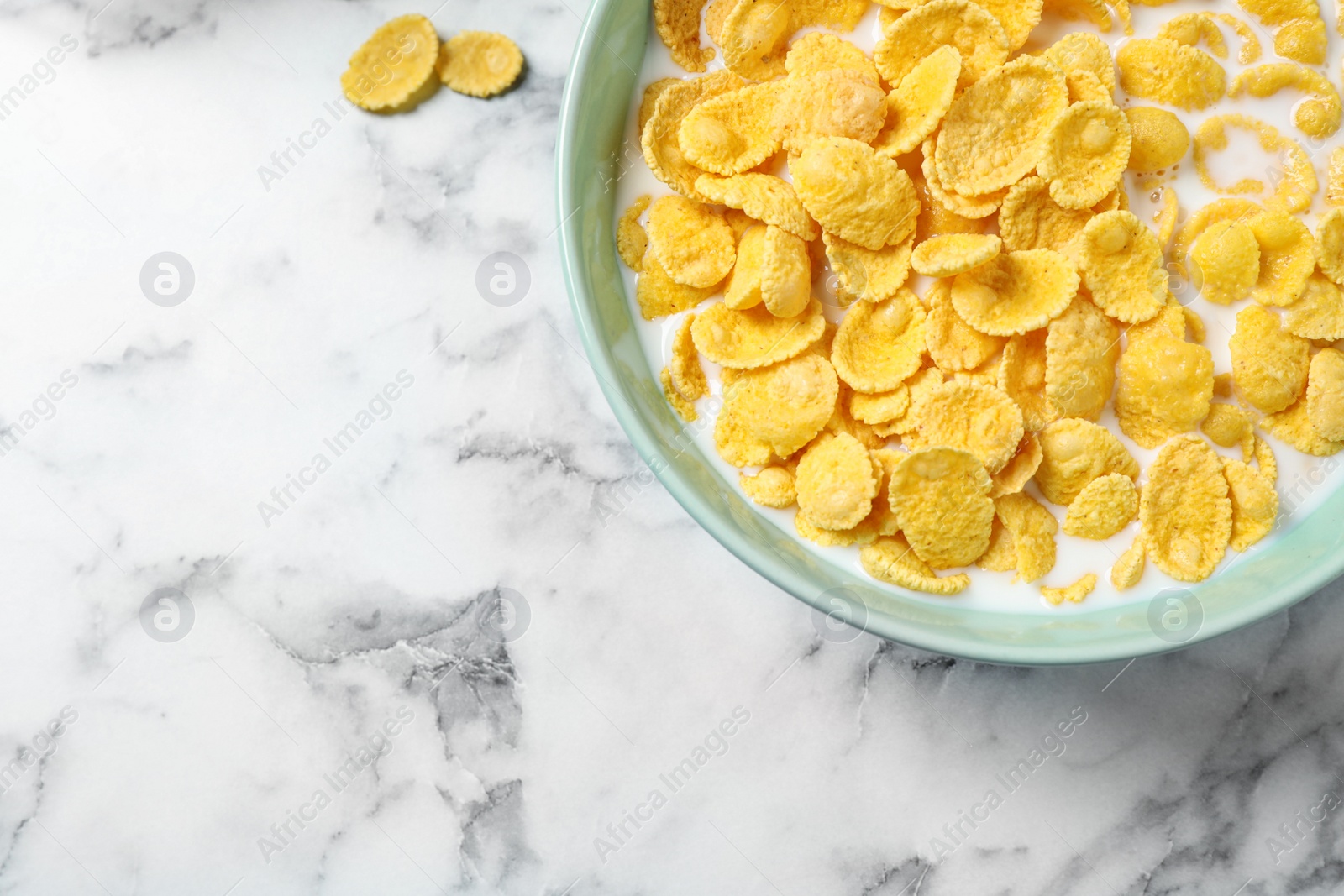 Photo of Tasty crispy corn flakes with milk on marble table, flat lay. Space for text