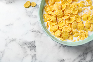 Photo of Tasty crispy corn flakes with milk on marble table, flat lay. Space for text
