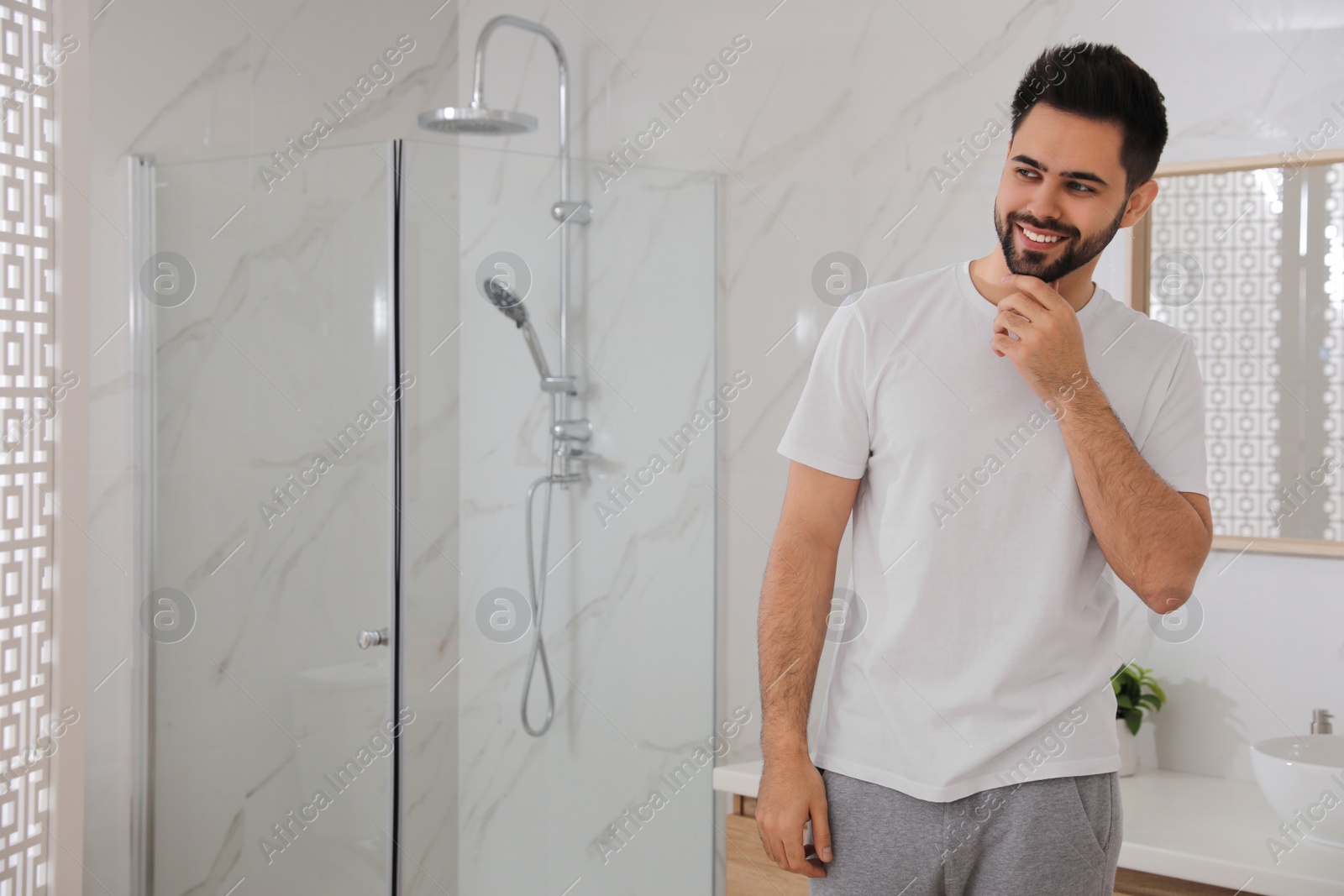 Photo of Handsome young man after shaving in bathroom, space for text