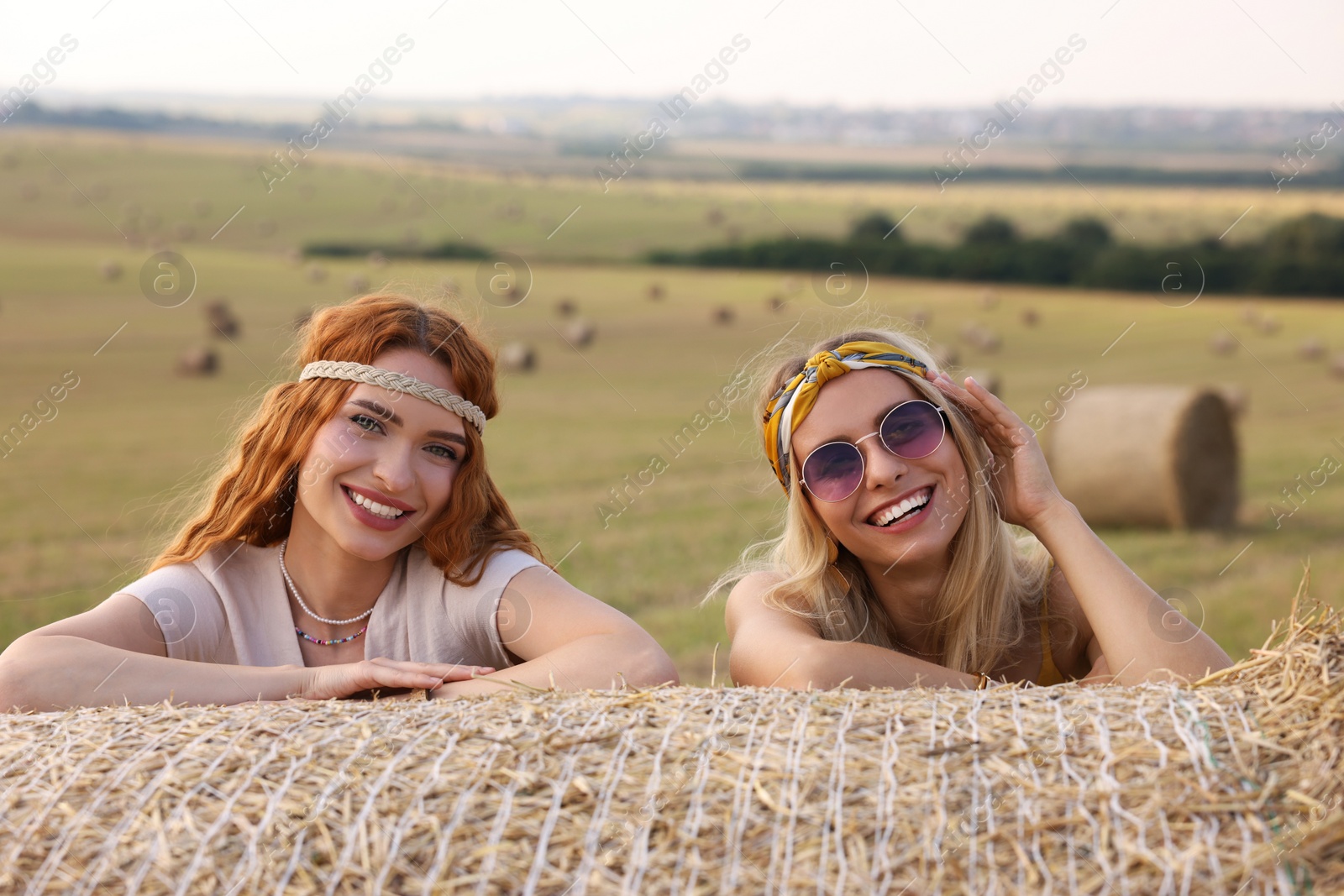 Photo of Beautiful hippie women near hay bale in field