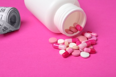 Photo of Weight loss pills, bottle and measuring tape on color background