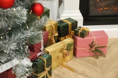 Many different gifts near Christmas tree and fireplace indoors