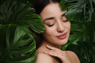 Image of Beautiful young woman feeling harmony while enjoying nature. Girl surrounded by green leaves