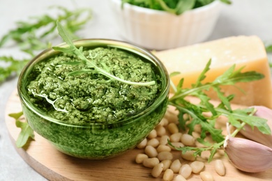 Photo of Bowl of tasty arugula pesto and ingredients on table