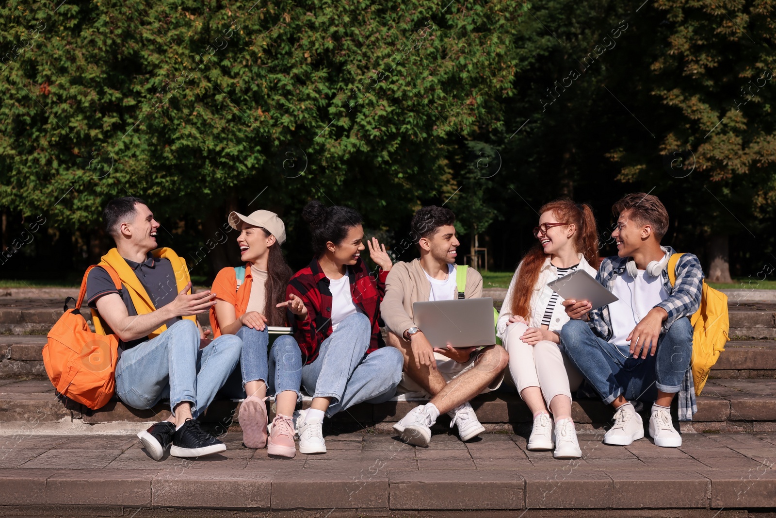 Photo of Group of happy young students learning together in park