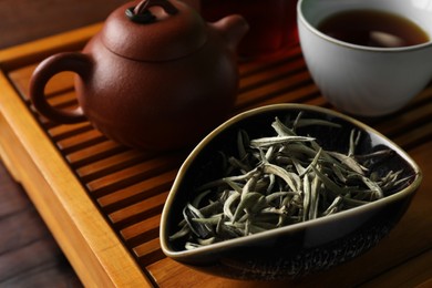 Photo of Aromatic Baihao Yinzhen tea and teapot on wooden tray, closeup. Traditional ceremony