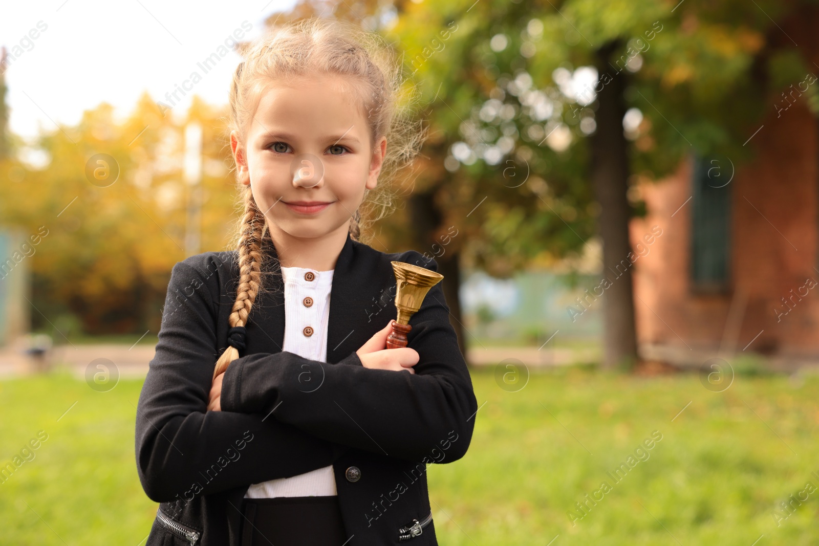 Photo of Pupil with school bell outdoors on sunny day, space for text