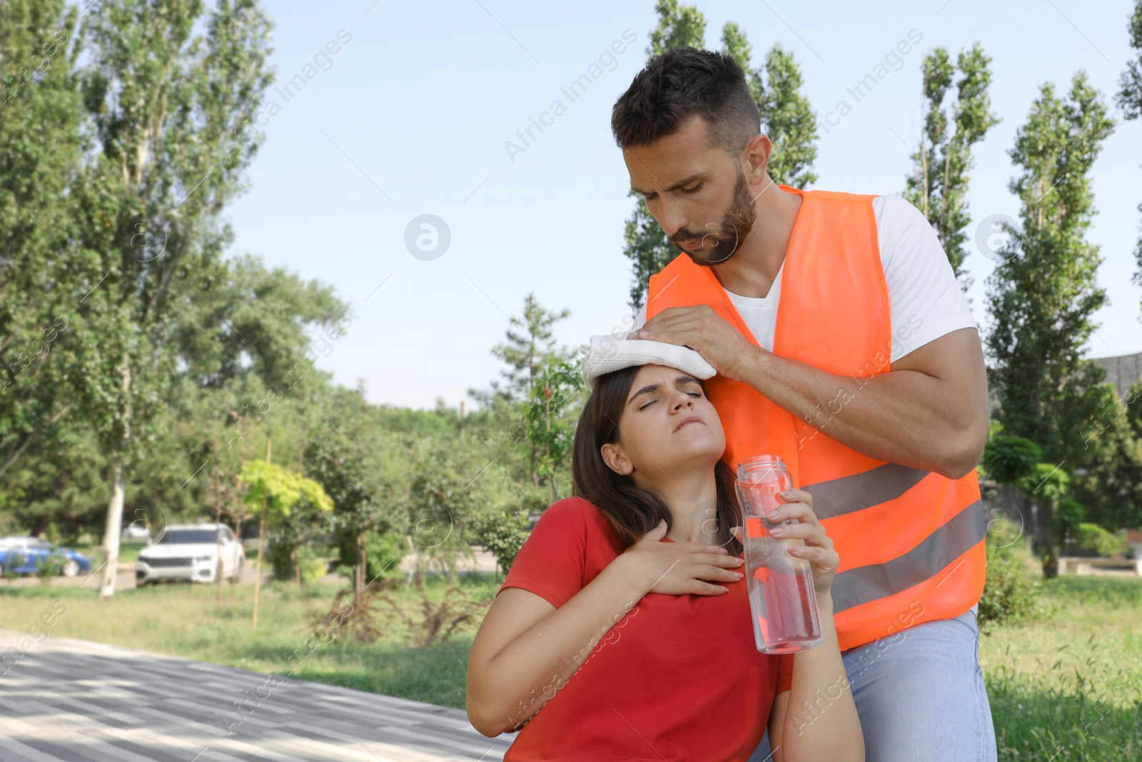 Photo of Worker helping woman on city street. Suffering from heat stroke