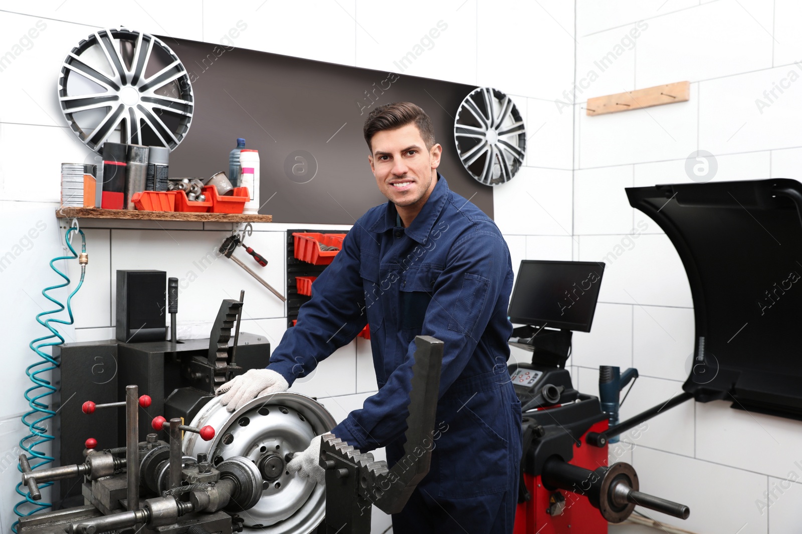 Photo of Man working with car disk lathe machine at tire service